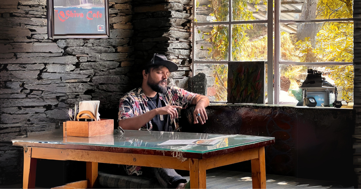 A solo traveller (Vinay Bharadwaj) sitting at a cafe]