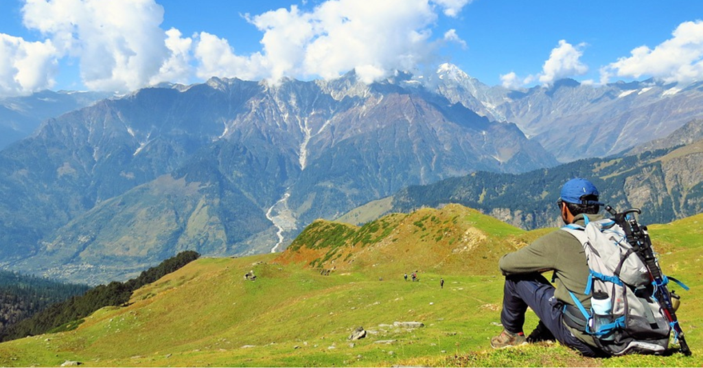 A man (Vinay) sitting at a mountaintop, watching the valley beneath