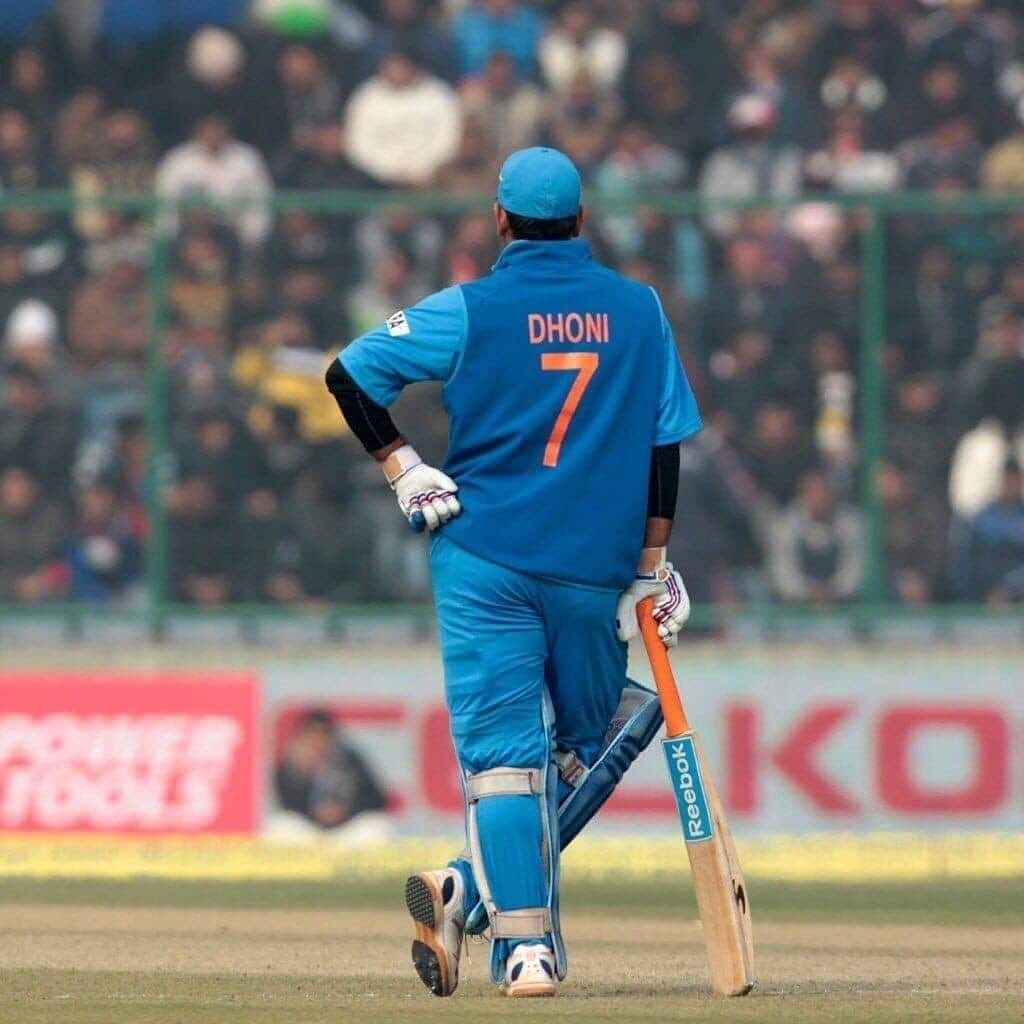 Dhoni standing on the field with his jersey showing number 7