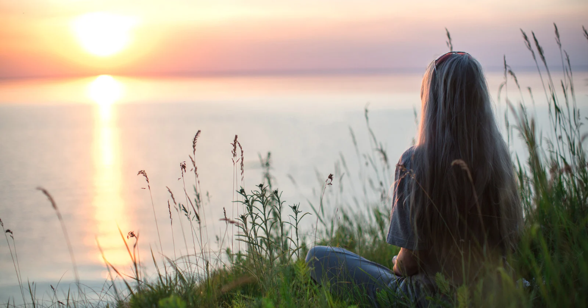 A person calmly sitting in a natural setting and sensing the environment around