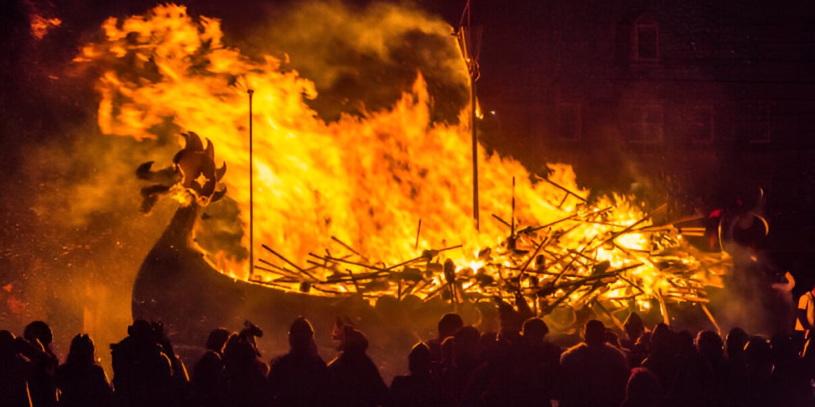 Vikings carrying torches during the Up Helly Aa fire festival in Scotland with burning longship
